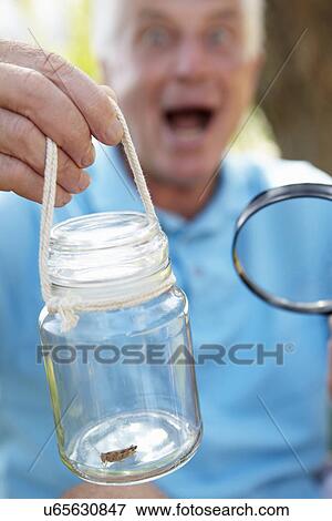 Stock Photo - Senior man with cricket in a jar. Fotosearch