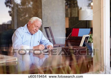 Senior Man Writing Memoirs In Book Sitting At Desk View Large Photo Image Picture - Senior Man Writing Memoirs In Book Sitting At Desk. Fotosearch