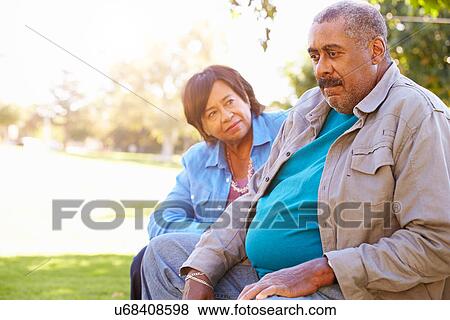 Stock Photo - Senior Woman Comforting Unhappy Senior Husband Outdoors. Fotosearch