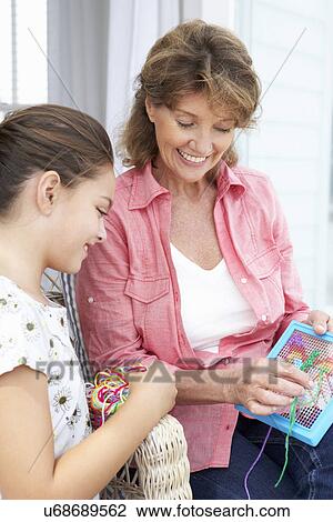 Stock Image - Senior woman doing cross stitch with granddaughter. Fotosearch