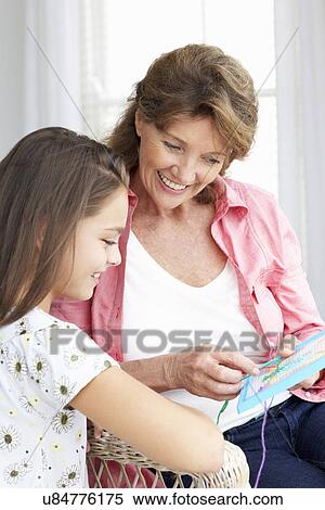 Stock Photography - Senior woman doing cross stitch with granddaughter. Fotosearch