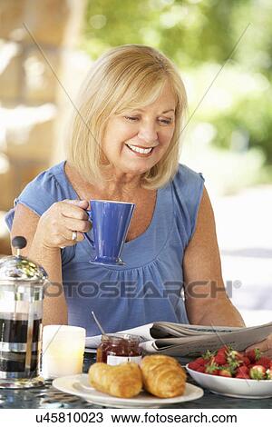 Senior woman eating breakfast outdoors View Large Photo Image Stock Image - Senior woman eating breakfast outdoors. Fotosearch