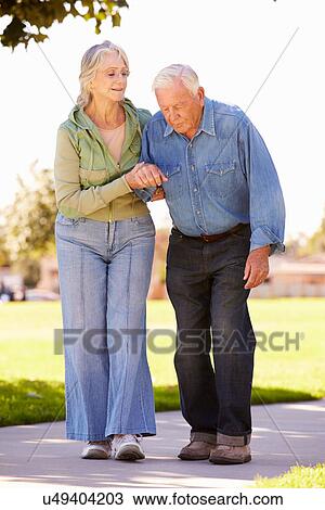 Senior Woman Helping Husband As They Walk In Park Together View Large Photo Image Stock Image - Senior Woman Helping Husband As They Walk In Park Together. Fotosearch