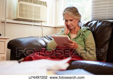 Stock Image - Senior Woman Keeping Warm Under Blanket With Photograph. Fotosearch