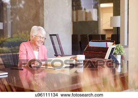 Picture - Senior Woman Looking At Photo Album Through Window. Fotosearch