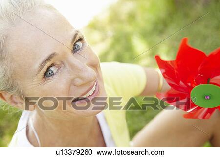 Stock Image - Senior woman outdoors with toy windmill. Fotosearch