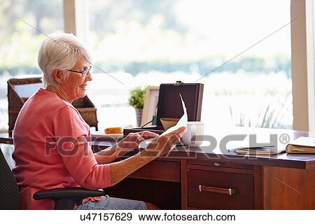 Stock Photo - Senior Woman Putting Letter Into Keepsake Box. Fotosearch