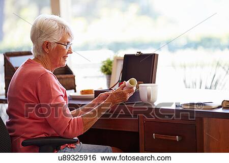 Stock Photograph - Senior Woman Putting Will Into Box. Fotosearch
