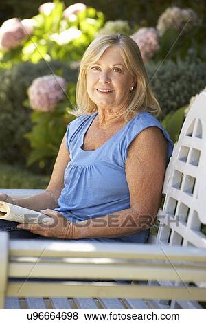 Stock Photo - Senior woman reading in garden. Fotosearch