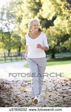 Stock Image - Senior woman running in park. Fotosearch