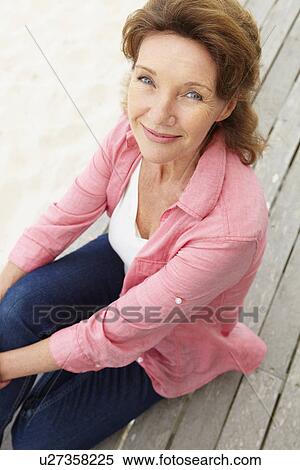 Stock Photography - Senior woman sitting by beach. Fotosearch