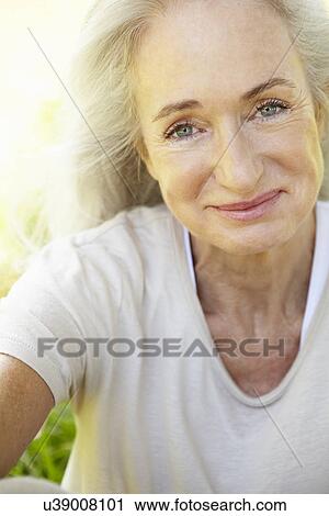 Stock Image - Senior woman sitting on grass. Fotosearch
