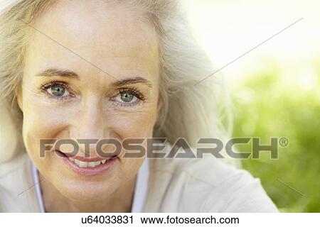Stock Image - Senior woman sitting on grass. Fotosearch