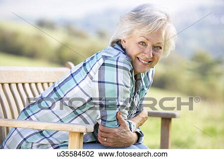 Stock Image - Senior woman sitting outdoors. Fotosearch