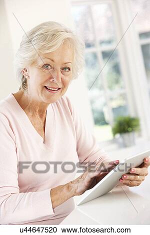 Senior woman using tablet at home View Large Photo Image Stock Image - Senior woman using tablet at home. Fotosearch
