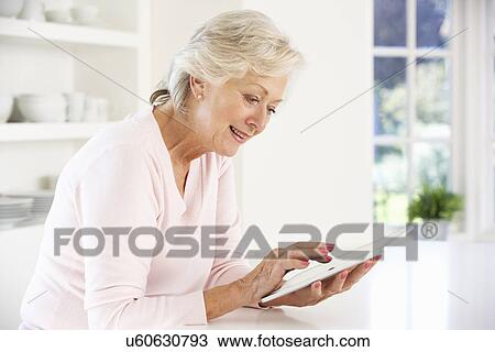 Senior woman using tablet at home View Large Photo Image Stock Image - Senior woman using tablet at home. Fotosearch