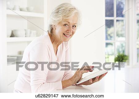Stock Photo - Senior woman using tablet at home. Fotosearch