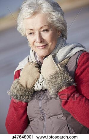 Stock Image - Senior Woman Walking On Winter Beach. Fotosearch