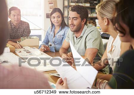 Stock Photo - Six Architects Sitting Around Table Having Meeting. Fotosearch