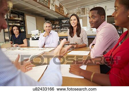 Stock Photograph - Six Architects Sitting Around Table Having Meeting. Fotosearch