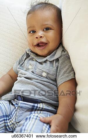 Stock Image - Smiling Baby Boy Lying On Back At Home. Fotosearch