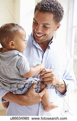 Smiling Father Standing By Window With Baby Son At Home View Large Photo Image Stock Photography - Smiling Father Standing By Window With Baby Son At Home. Fotosearch