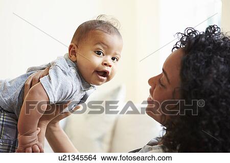 Picture - Smiling Mother Playing With Baby Son At Home. Fotosearch