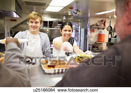 Picture - Staff Serving Food In Homeless Shelter Kitchen. Fotosearch