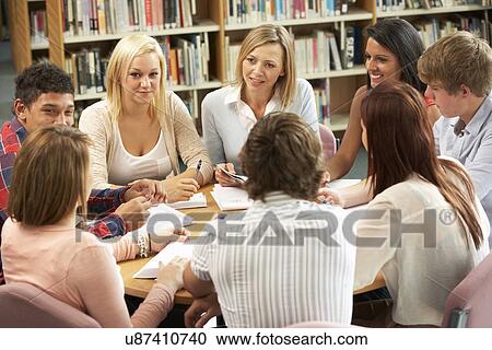 Stock Image - Students and tutor working in library. Fotosearch