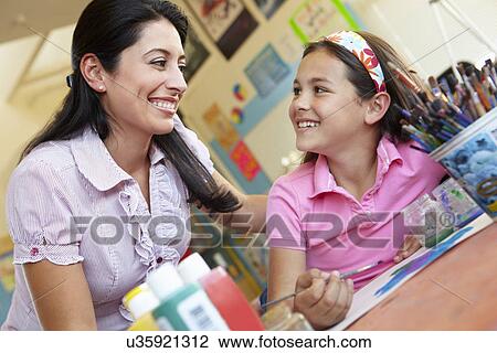 Stock Image - Teacher and pupil in art class. Fotosearch