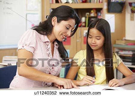 Stock Image - Teacher and schoolgirl in class. Fotosearch