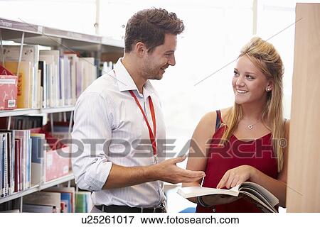 Stock Photo - Teacher Helping College Student With Studies In Library. Fotosearch