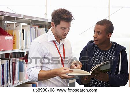 Stock Photo - Teacher Helping College Student With Studies In Library. Fotosearch