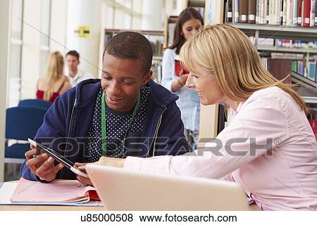 Teacher Helping College Student With Studies In Library View Large Photo Image Stock Photo - Teacher Helping College Student With Studies In Library. Fotosearch