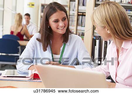 Teacher Helping College Student With Studies In Library View Large Photo Image Stock Photography - Teacher Helping College Student With Studies In Library. Fotosearch