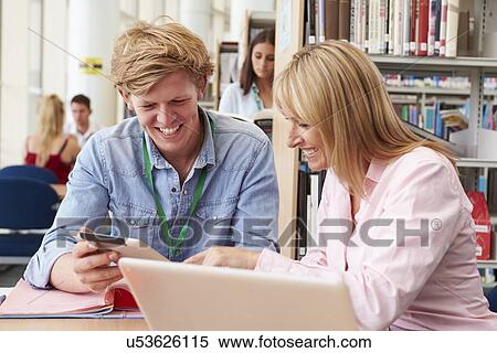 Stock Photography - Teacher Helping College Student With Studies In Library. Fotosearch