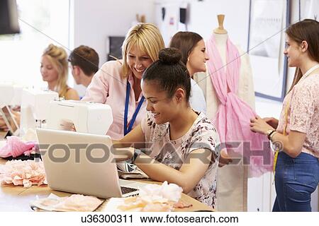 Stock Image - Teacher Helping College Students Studying Fashion And Design. Fotosearch