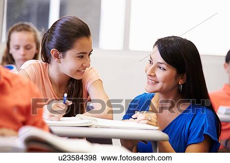 Stock Photo - Teacher Helping Female High School Student In Classroom. Fotosearch