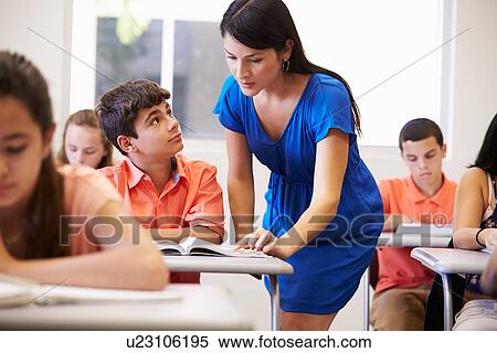 Stock Photography - Teacher Helping Male High School Student In Classroom. Fotosearch