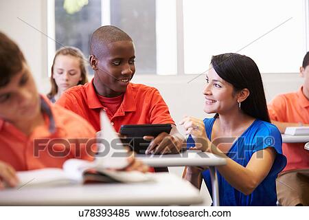 Stock Photography - Teacher Helping Male High School Student In Classroom. Fotosearch