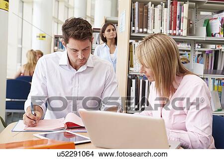 Picture - Teacher Helping Mature Student With Studies In Library. Fotosearch