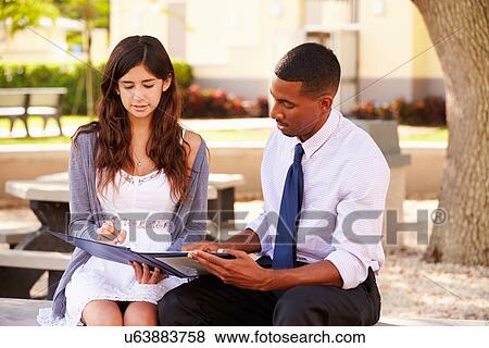 Teacher Sitting Outdoors Helping Female Student With Work View Large Photo Image Stock Photo - Teacher Sitting Outdoors Helping Female Student With Work. Fotosearch
