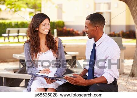 Teacher Sitting Outdoors Helping Female Student With Work View Large Photo Image Stock Photo - Teacher Sitting Outdoors Helping Female Student With Work. Fotosearch