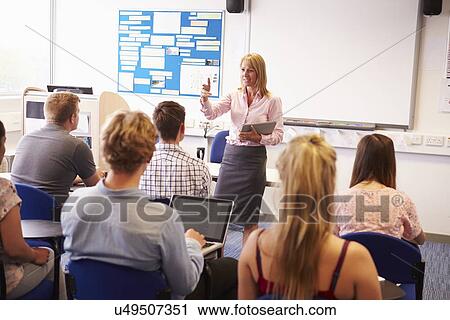 Stock Image - Teacher With College Students Giving Lesson In Classroom. Fotosearch