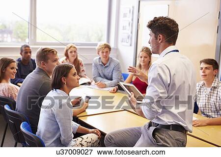 Stock Photo - Teacher With College Students Giving Lesson In Classroom. Fotosearch