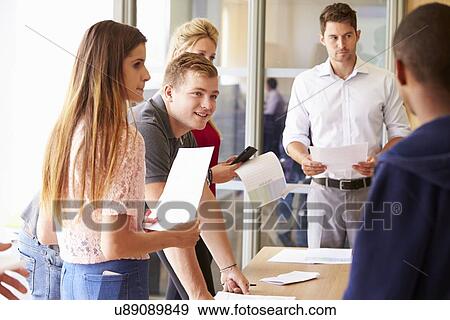 Teacher With College Students Standing By Desks In Classroom View Large Photo Image Stock Photo - Teacher With College Students Standing By Desks In Classroom. Fotosearch