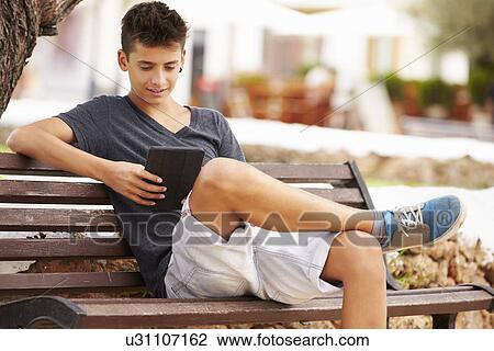 Teenage Boy On Park Bench Using Digital Tablet View Large Photo Image Stock Image - Teenage Boy On Park Bench Using Digital Tablet. Fotosearch