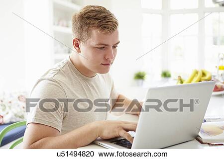 Stock Image - Teenage Boy Studying On Laptop At Home. Fotosearch