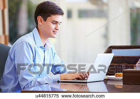 Stock Photography - Teenage Boy Using Laptop On Desk At Home. Fotosearch