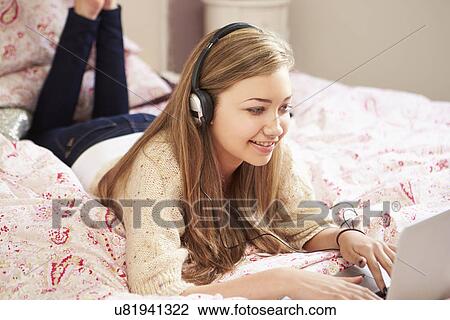 Teenage Girl Lying On Bed Using Laptop Wearing Headphones View Large Photo Image Stock Image - Teenage Girl Lying On Bed Using Laptop Wearing Headphones. Fotosearch